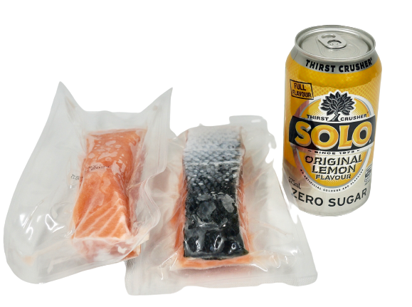 salmon portions in vacuum seal next to can of drink for size reference no background