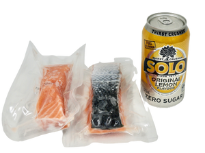 salmon portions in vacuum seal next to can of drink for size reference no background